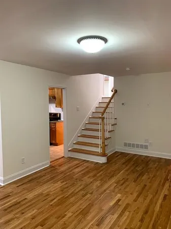 a view of a livingroom with wooden floor and stairs