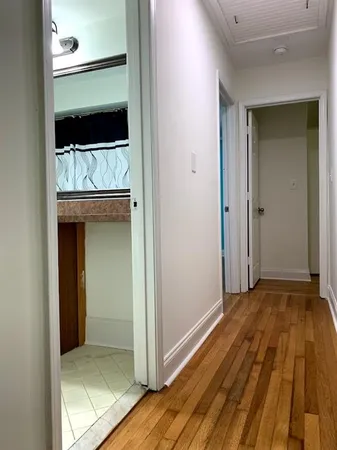 a view of a hallway with wooden floor and cabinet