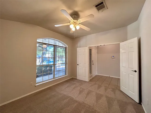 a view of an empty room with a ceiling fan and window