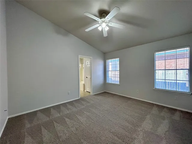 an empty room with chandelier fan and windows