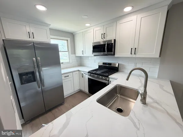 a kitchen with stainless steel appliances granite countertop a refrigerator a sink a stove a microwave and cabinets