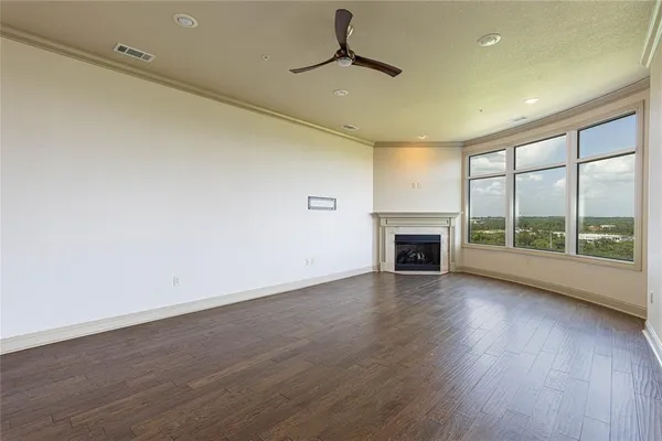 a view of an empty room with wooden floor fireplace and a window