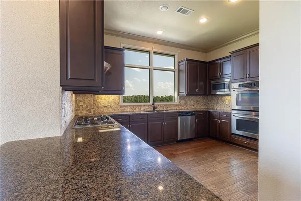 a kitchen with stainless steel appliances granite countertop a stove a sink and a refrigerator