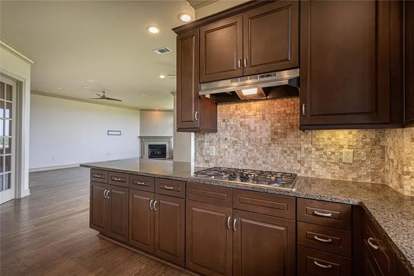 a kitchen with stainless steel appliances granite countertop wooden cabinets and a stove top oven