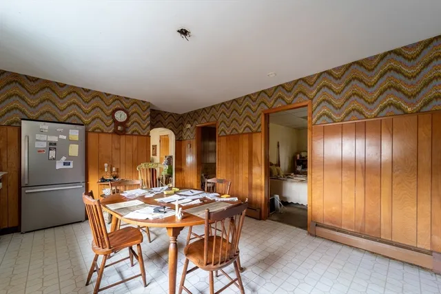 a dining hall with stainless steel appliances kitchen island granite countertop a refrigerator and wooden cabinets