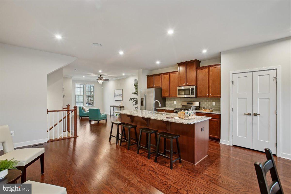 2105 Hemlock Bay Road Dumfries, VA 22026 - Photo 5 of 48 a kitchen with stainless steel appliances a dining table chairs stove and wooden floor