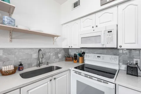 a kitchen with white cabinets and sink
