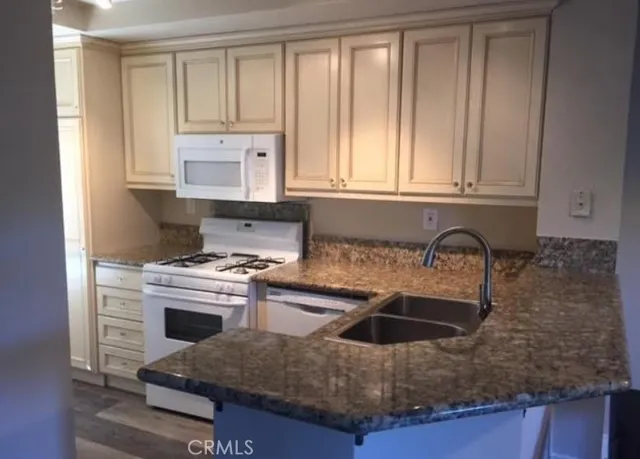 a kitchen with granite countertop a sink stove and cabinets