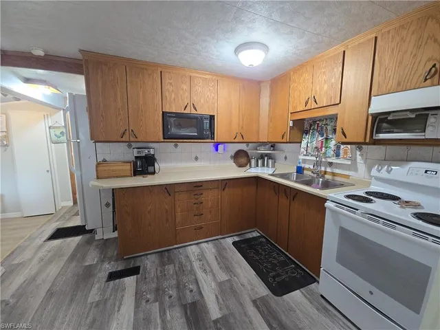 a kitchen with a sink a stove a microwave and wooden cabinets