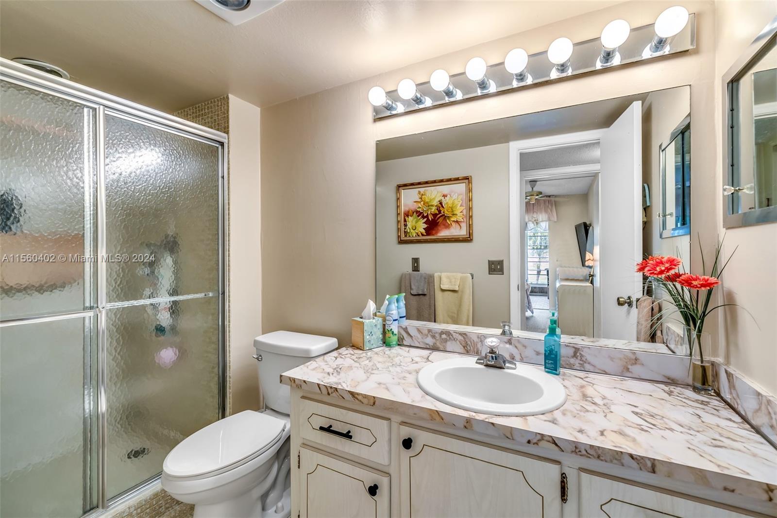 2011 Lyndhurst H, Unit 2011 Deerfield Beach, FL 33442 - Photo 15 of 35 a bathroom with a granite countertop toilet a sink and a mirror