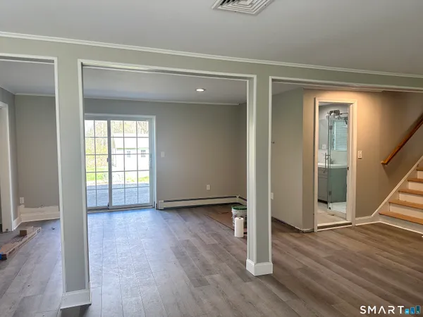 a view of an empty room with wooden floor and a window