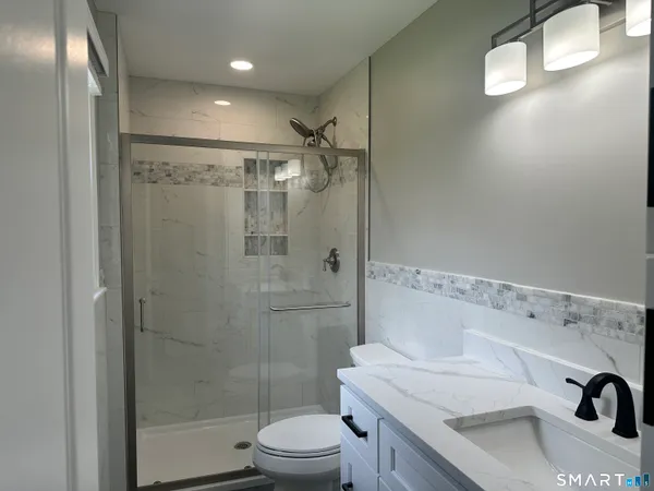 a bathroom with a sink a toilet and shower