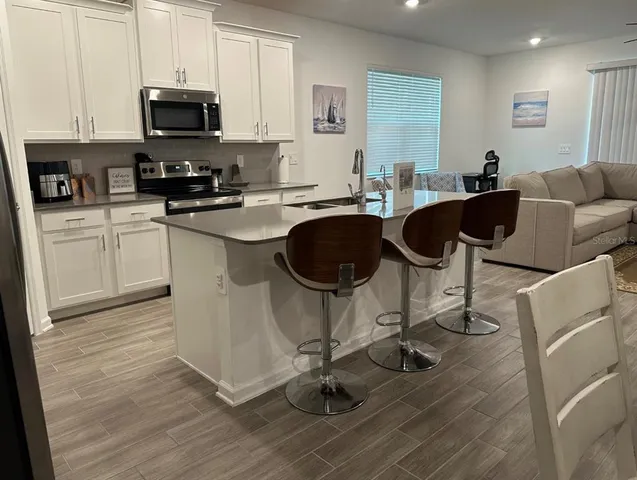 a kitchen with granite countertop a table chairs a sink dishwasher stove and cabinets with wooden floor