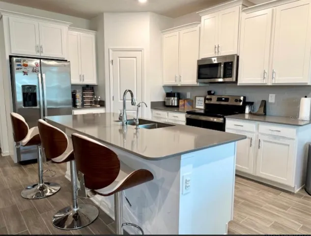 a kitchen with kitchen island granite countertop a stove a sink and a microwave