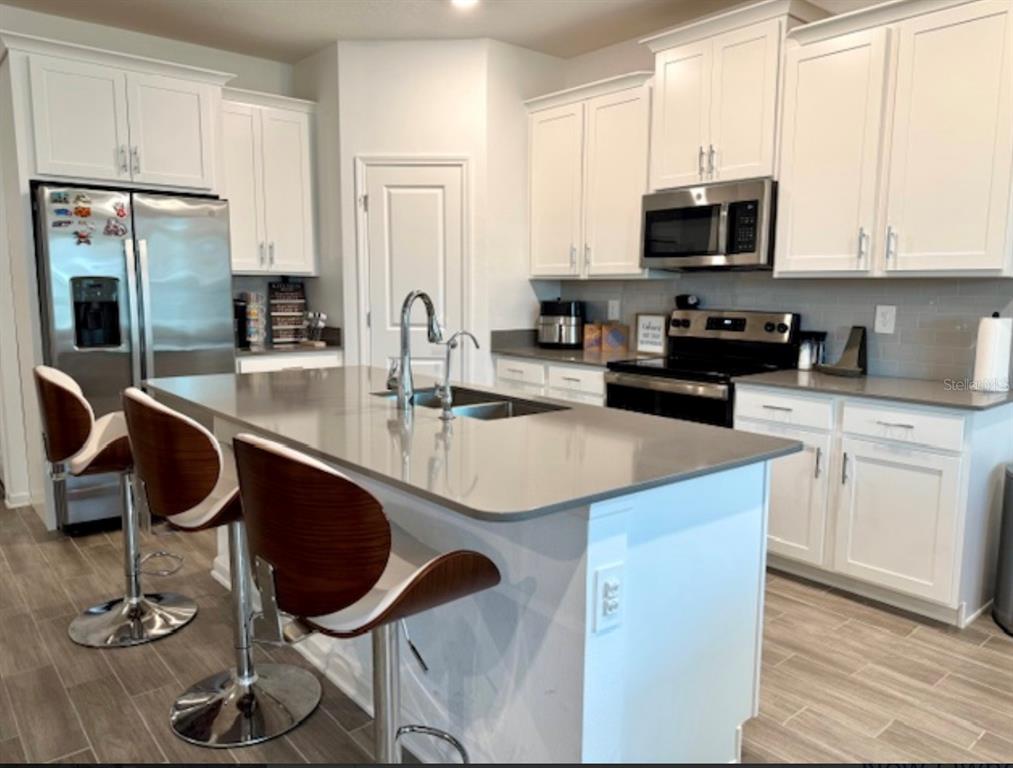 2759 Slash Way St. Cloud, FL 34771 - Photo 2 of 45 a kitchen with kitchen island granite countertop a stove a sink and a microwave