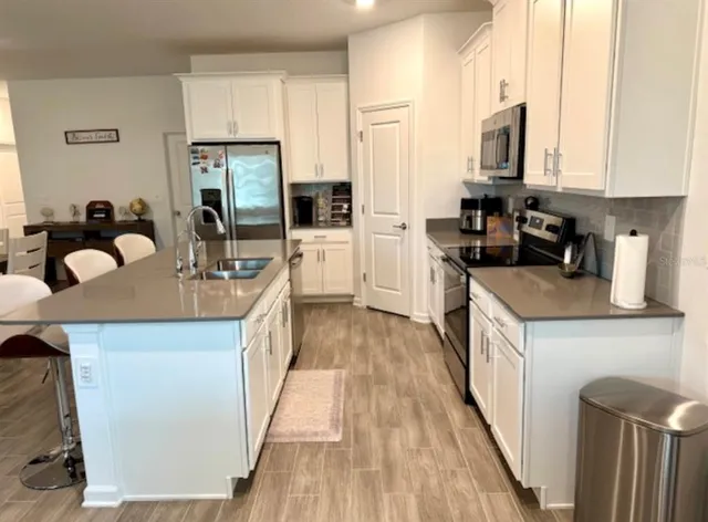 a kitchen with kitchen island granite countertop a sink a counter top space cabinets and stainless steel appliances