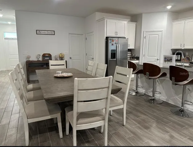 a kitchen with a dining table chairs and refrigerator
