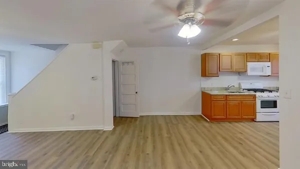a room with a wooden floor and white kitchen