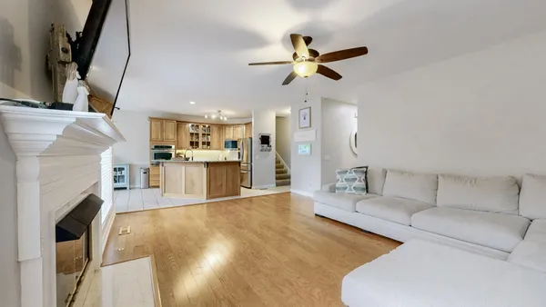 a living room with stainless steel appliances furniture a fireplace a flat screen tv and view kitchen