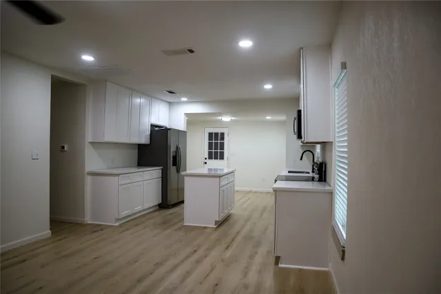 an empty room with a chandelier fan and windows