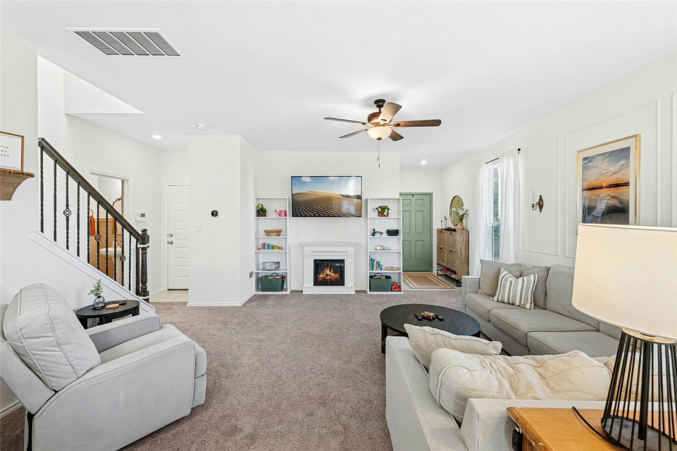 2001 Saskatoon Street Georgetown, TX 78626 - Photo 12 of 40 A cozy living area filled with natural light, featuring a gas fireplace flanked by decorative built-ins. This inviting space also includes carpet flooring and a ceiling fan, creating a warm and comfortable atmosphere perfect for everyday living and relaxation.