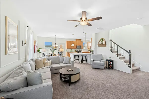 a living room with furniture kitchen view and a chandelier