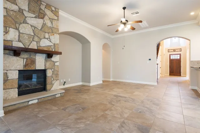 a view of an empty room with a fireplace and a chandelier fan