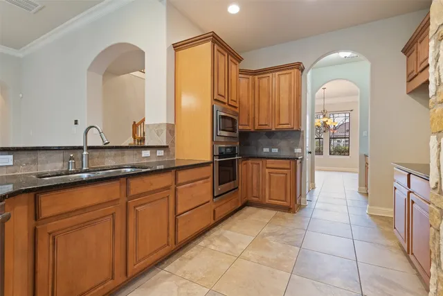 a large kitchen with granite countertop a sink and cabinets