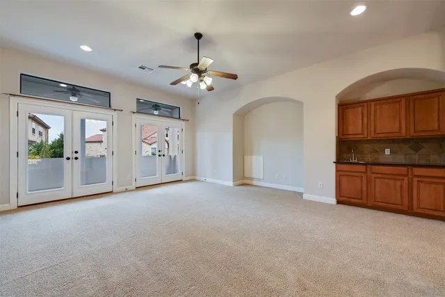 a view of an empty room with window cabinet and kitchen view