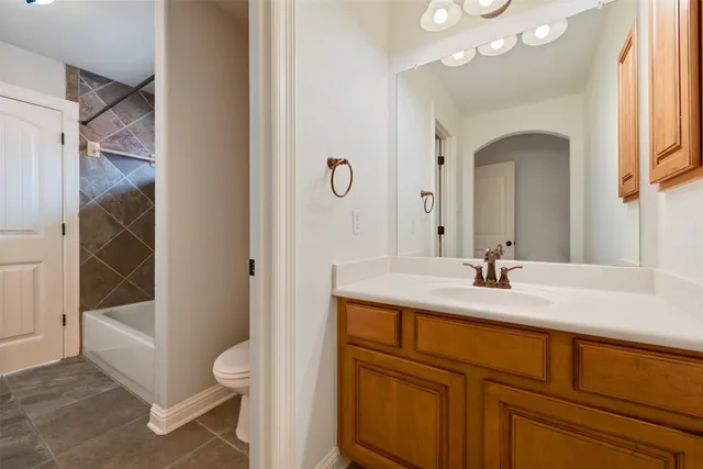 a bathroom with a granite countertop sink a toilet a mirror and shower
