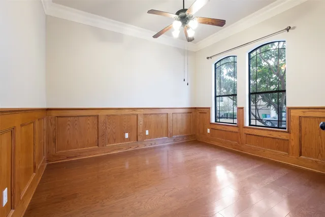 an empty room with windows and chandelier fan