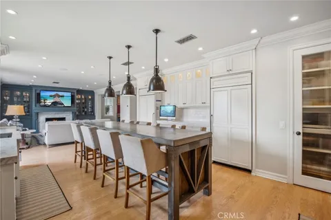 a view of a dining room and livingroom with furniture wooden floor a rug a flat screen tv a painting and a chandelier
