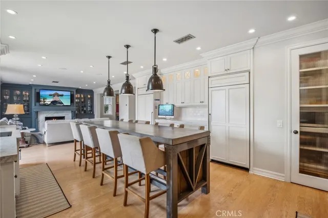 a view of a dining room and livingroom with furniture wooden floor a rug a flat screen tv a painting and a chandelier