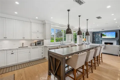a kitchen with stainless steel appliances granite countertop a table chairs sink and cabinets