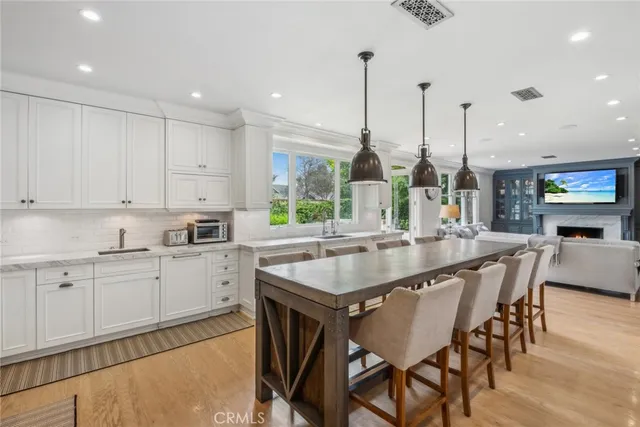 a kitchen with stainless steel appliances granite countertop a table chairs sink and cabinets