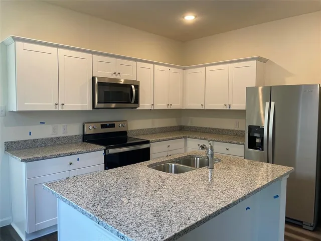 a kitchen with stainless steel appliances granite countertop a sink a stove and a microwave