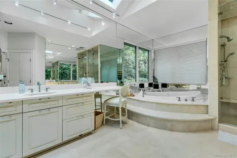 a bathroom with a tub a sink shower and mirror