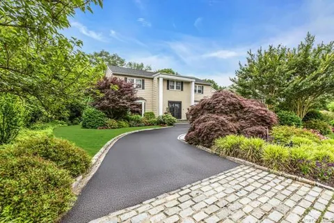 a view of a house with a small yard and a large tree