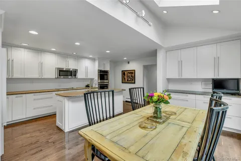 a kitchen with stainless steel appliances granite countertop a stove top oven a sink dishwasher a dining table and chairs with wooden floor