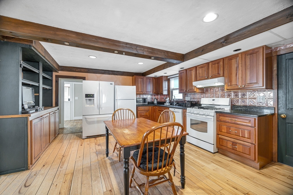 167 North Road Chelmsford, MA 01824 - Photo 11 of 38 a kitchen with stainless steel appliances granite countertop a stove top oven a sink dishwasher a dining table and chairs with wooden floor