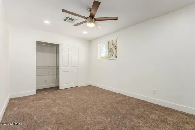 an empty room with a ceiling fan and a window