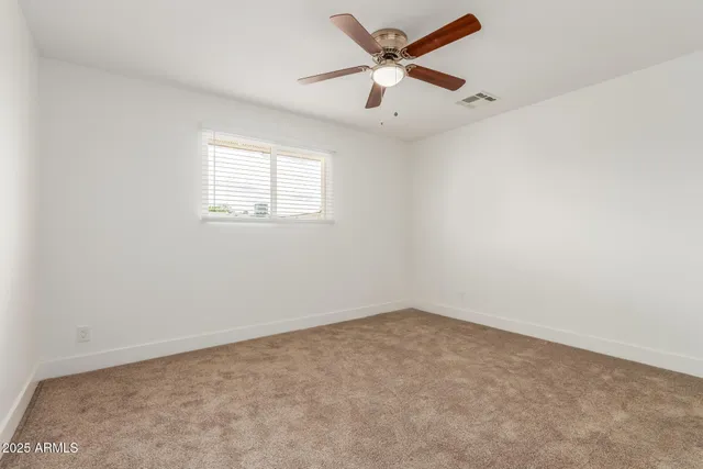 an empty room with a window and a ceiling fan