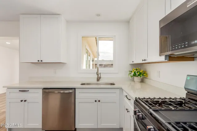 a kitchen with white cabinets and appliances