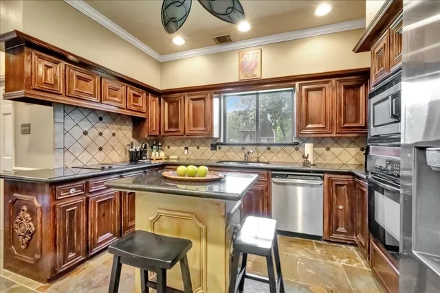 a kitchen with stainless steel appliances granite countertop a stove top oven a sink dishwasher and cabinets with wooden cabinets