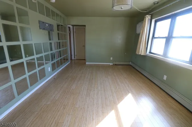a view of an empty room with a window and wooden floor