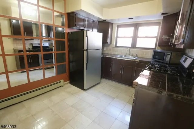 a kitchen with stainless steel appliances granite countertop a refrigerator a sink a stove and a refrigerator