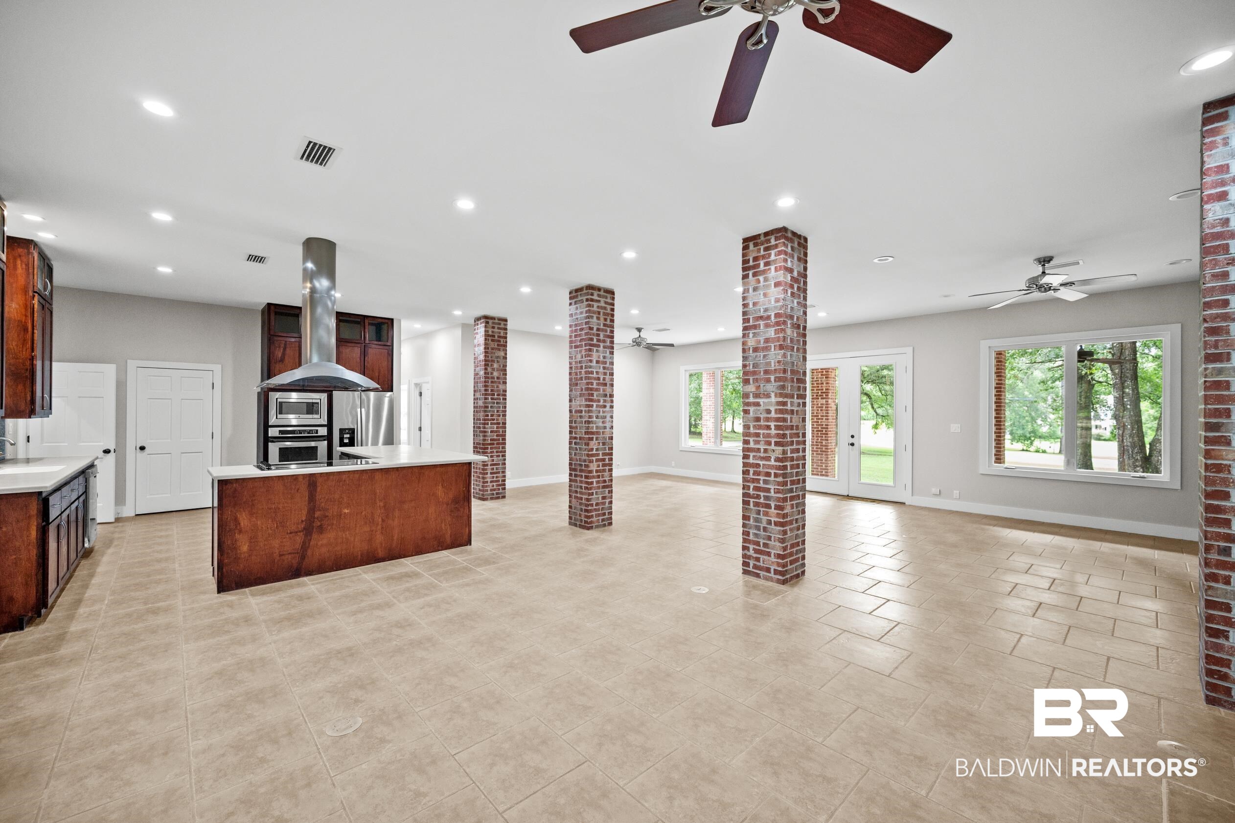 15031 Timber Ridge Drive Loxley, AL 36551 - Photo 10 of 43 Kitchen featuring appliances with stainless steel finishes, island range hood, light tile patterned floors, an island with sink, and ceiling fan