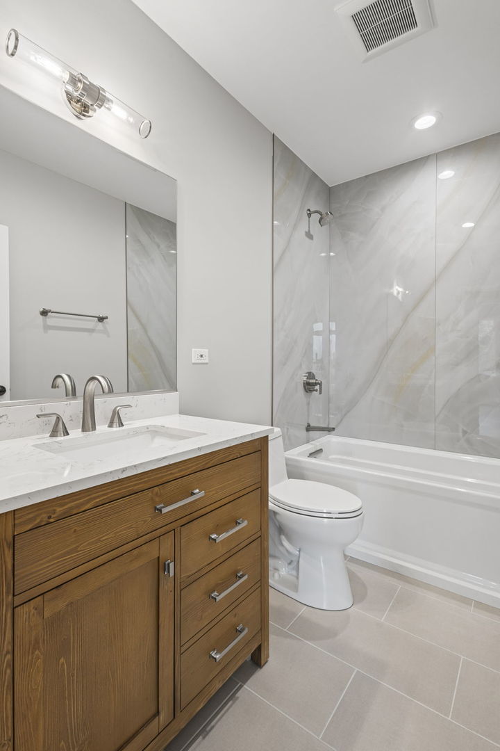 1036 Lake Street, Unit 3N Oak Park, IL 60301 - Photo 20 of 24 a bathroom with a toilet a sink a mirror a bathtub and vanity