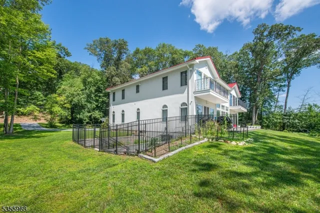 a view of a house next to a big yard and large trees