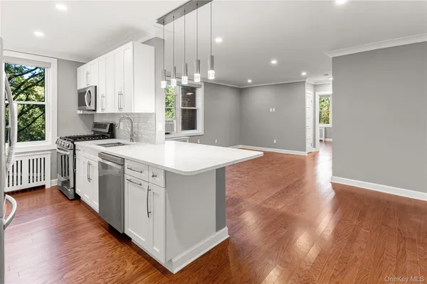 a kitchen with a stove a sink and white cabinets with wooden floor